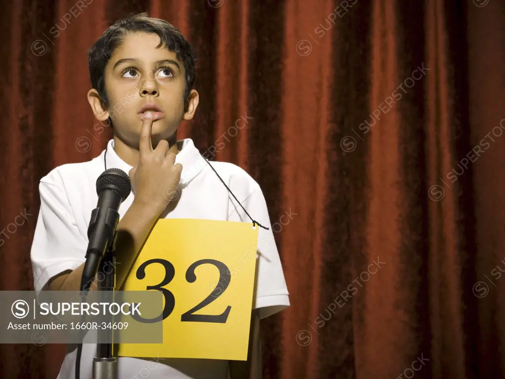 Boy contestant standing at microphone thinking