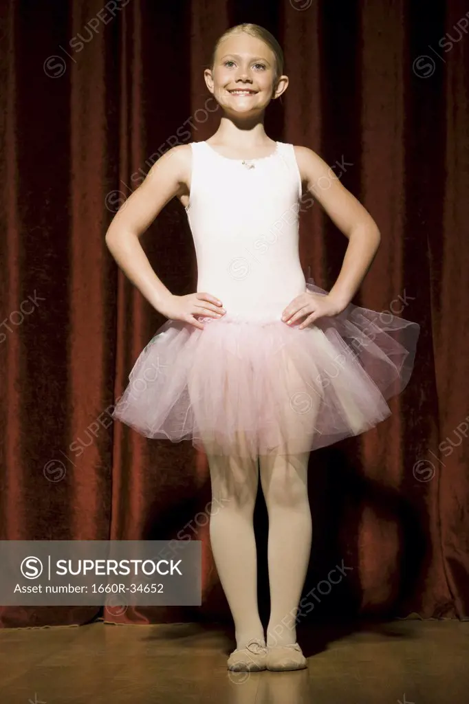 Ballerina girl standing with arms over head smiling