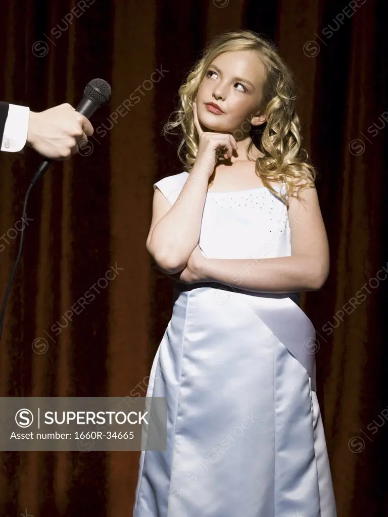 Girl beauty pageant contestant looking at man with microphone