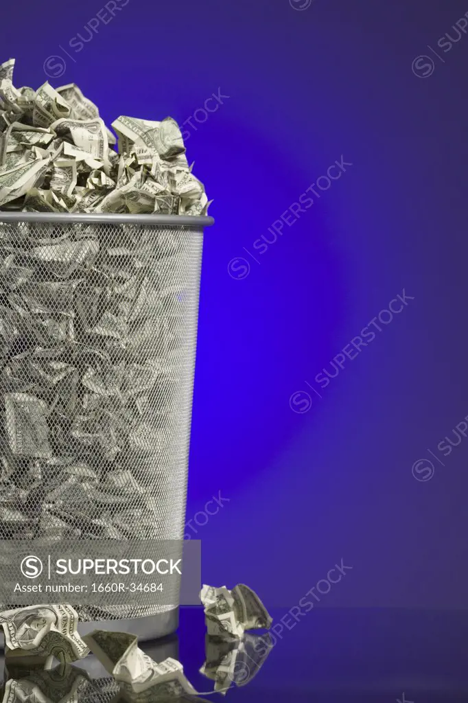 Crumpled money in waste paper basket
