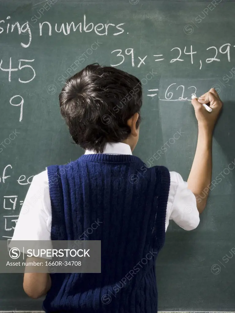 Rear view of boy at chalkboard doing math formulas