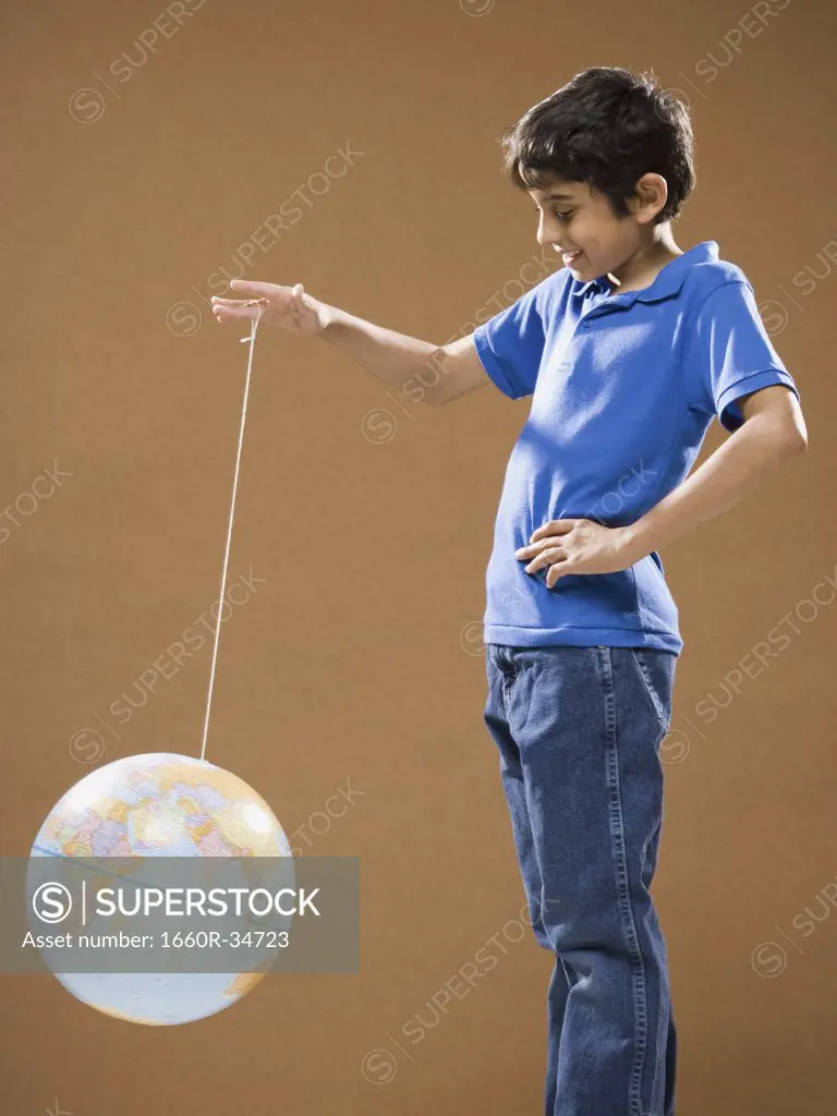 Boy holding string with globe attached smiling