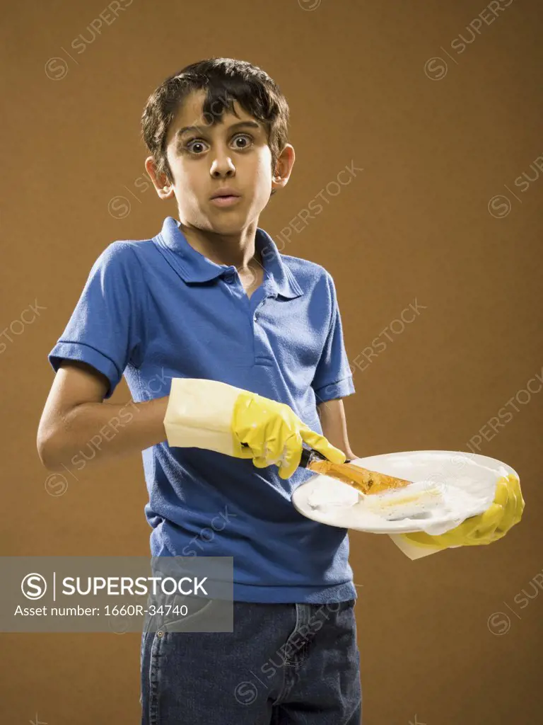 Boy with rubber gloves scrubbing plate
