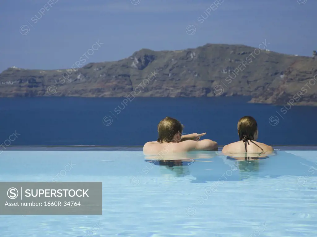 Rear view of couple in infinity pool with mountains