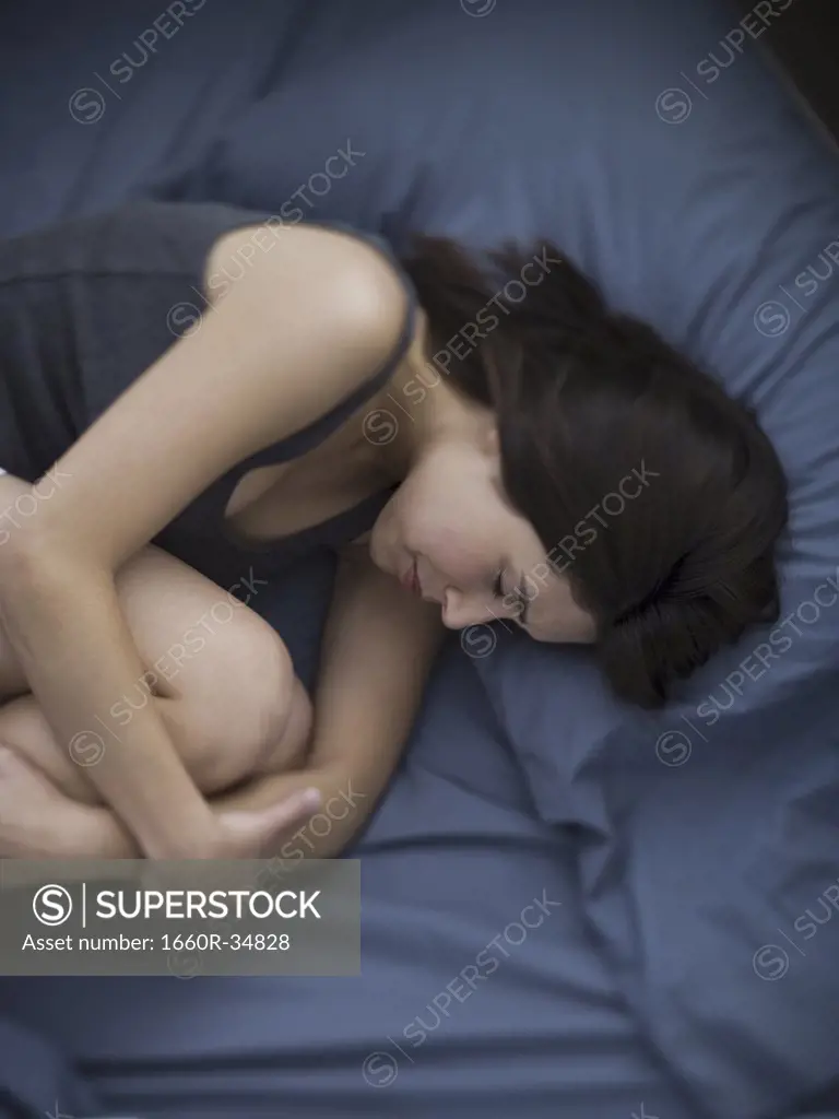Woman in bed sleeping curled up
