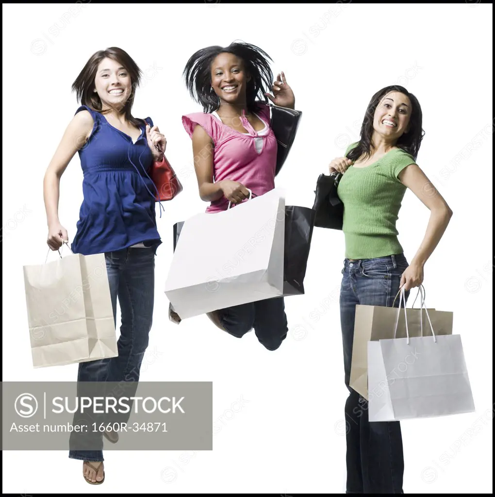 Three women with shopping bags smiling and leaping