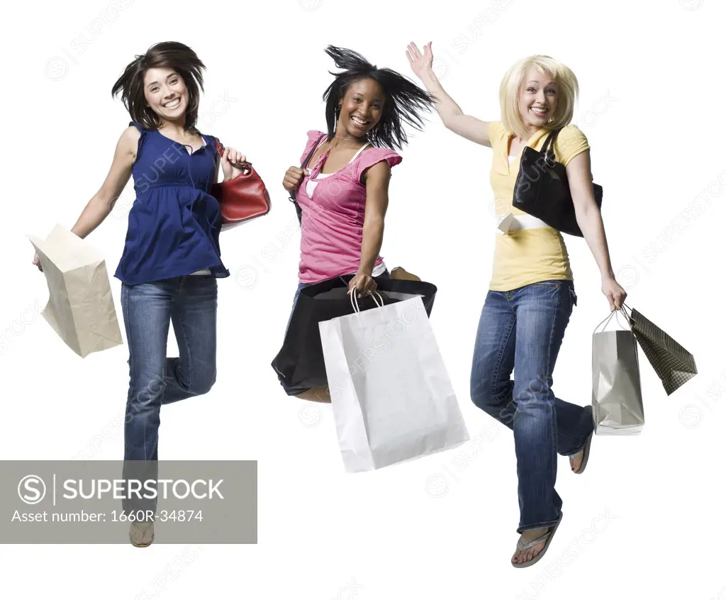 Three women with shopping bags smiling and leaping