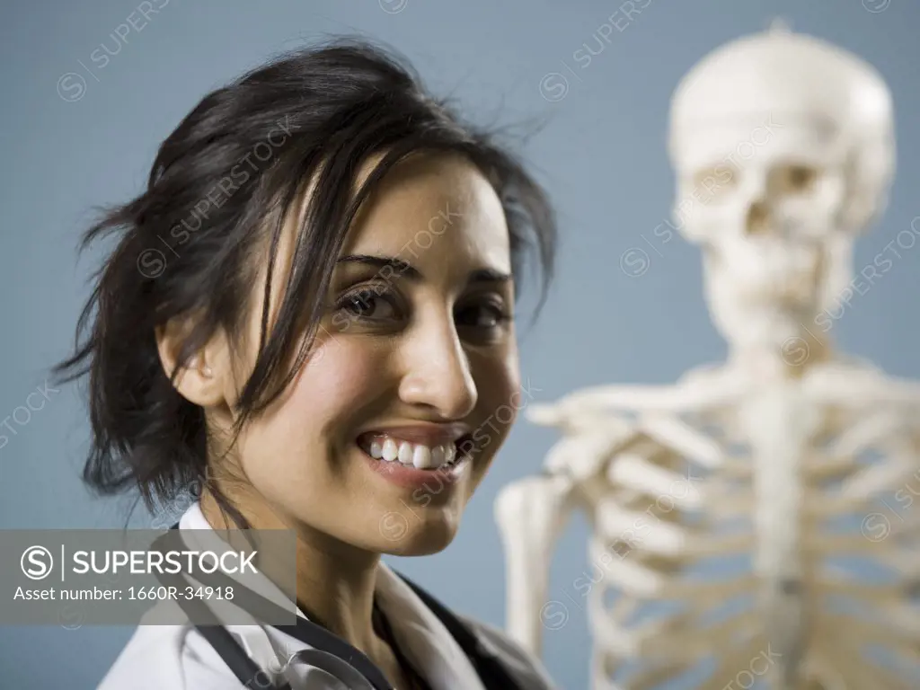 Female doctor smiling with skeleton in background