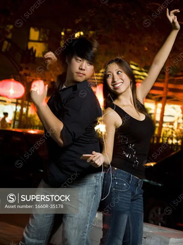 Couple listening to mp3 player outdoors dancing and smiling