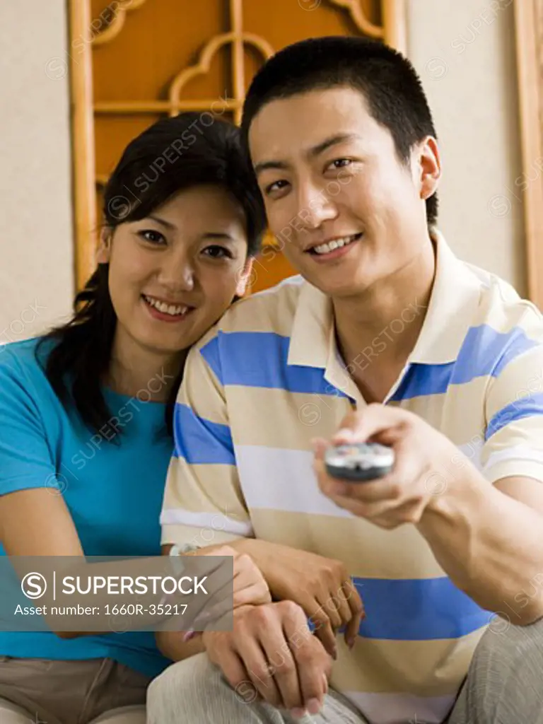 Couple sitting on sofa watching television smiling