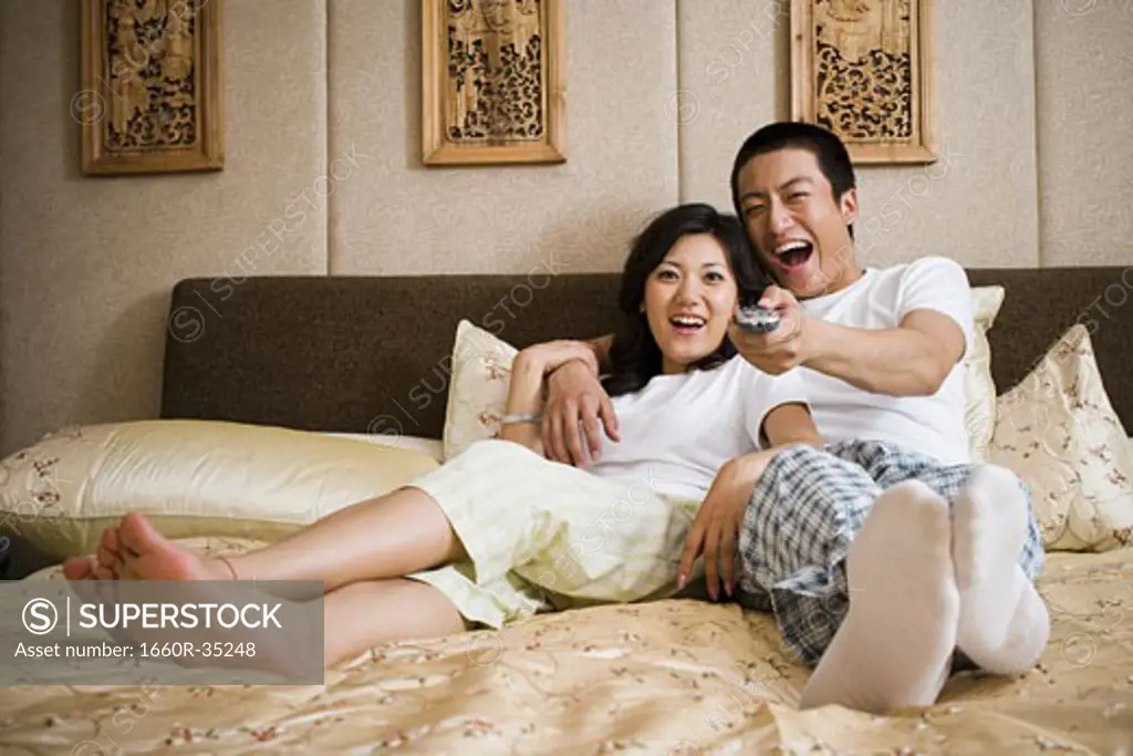 Couple in bed snuggling and watching television