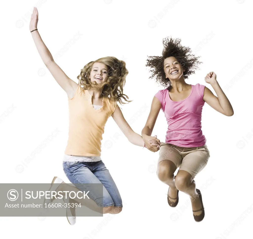Two girls with braces holding hands and leaping