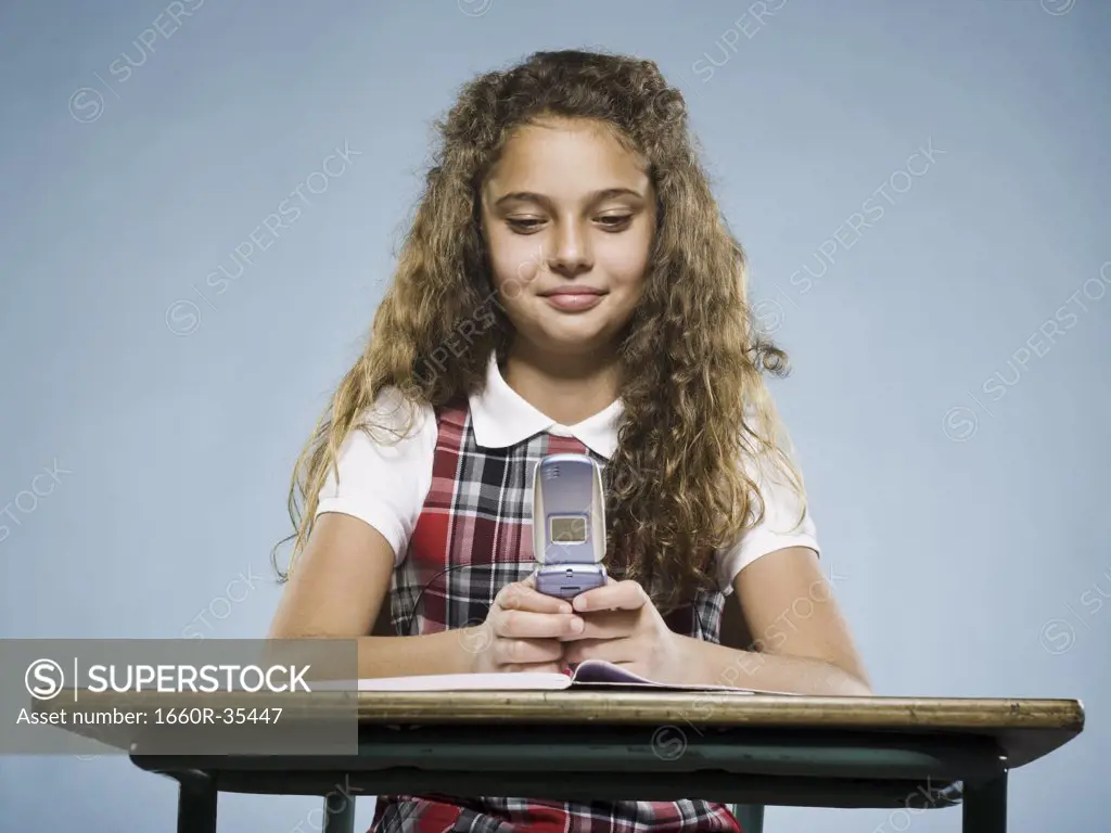 Girl sitting at desk with workbook and cell phone