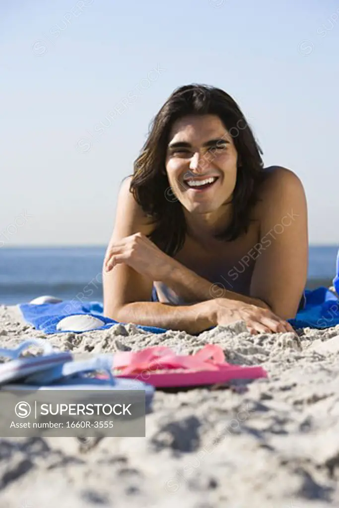Portrait of a young man lying on the beach smiling