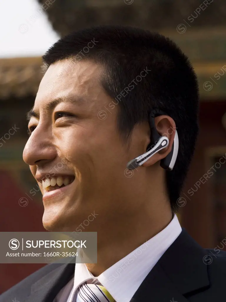 Businessman with headset smiling outdoors