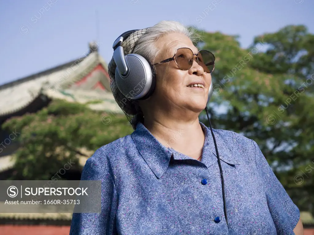 Mature woman outdoors with headphones smiling