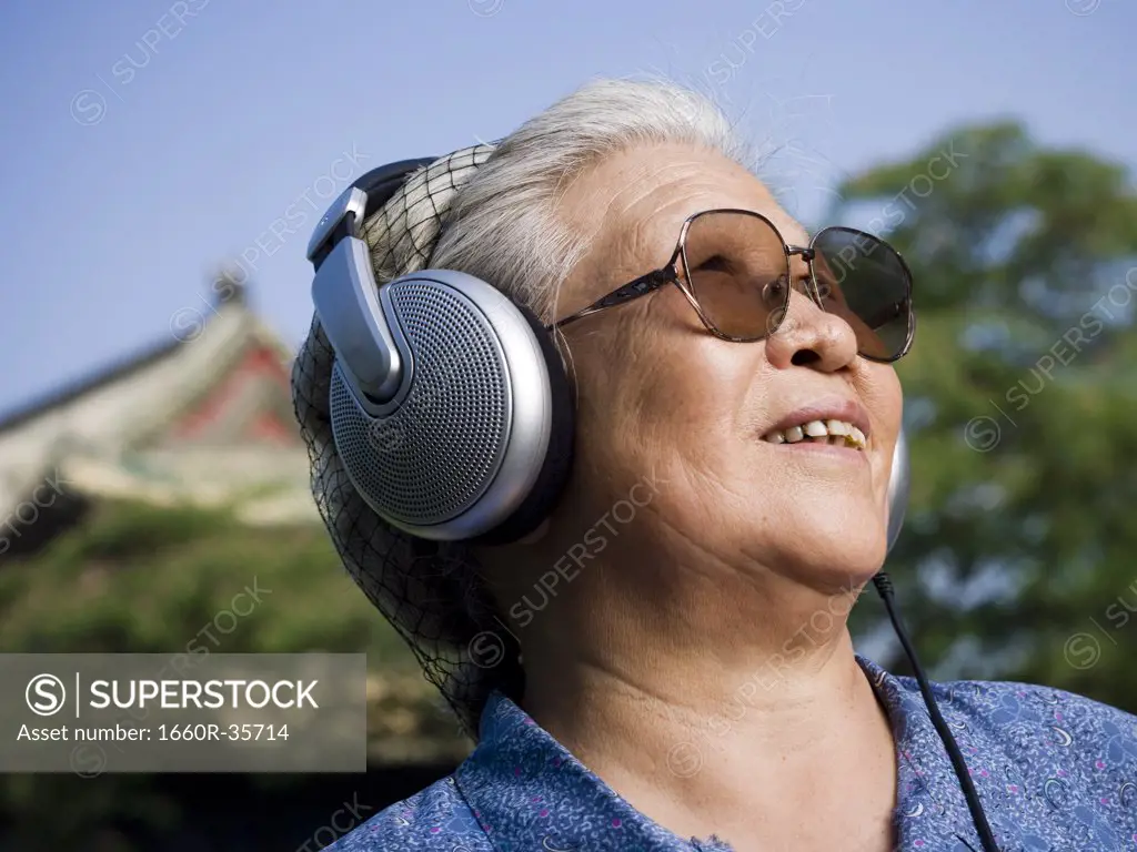 Mature woman outdoors with headphones smiling