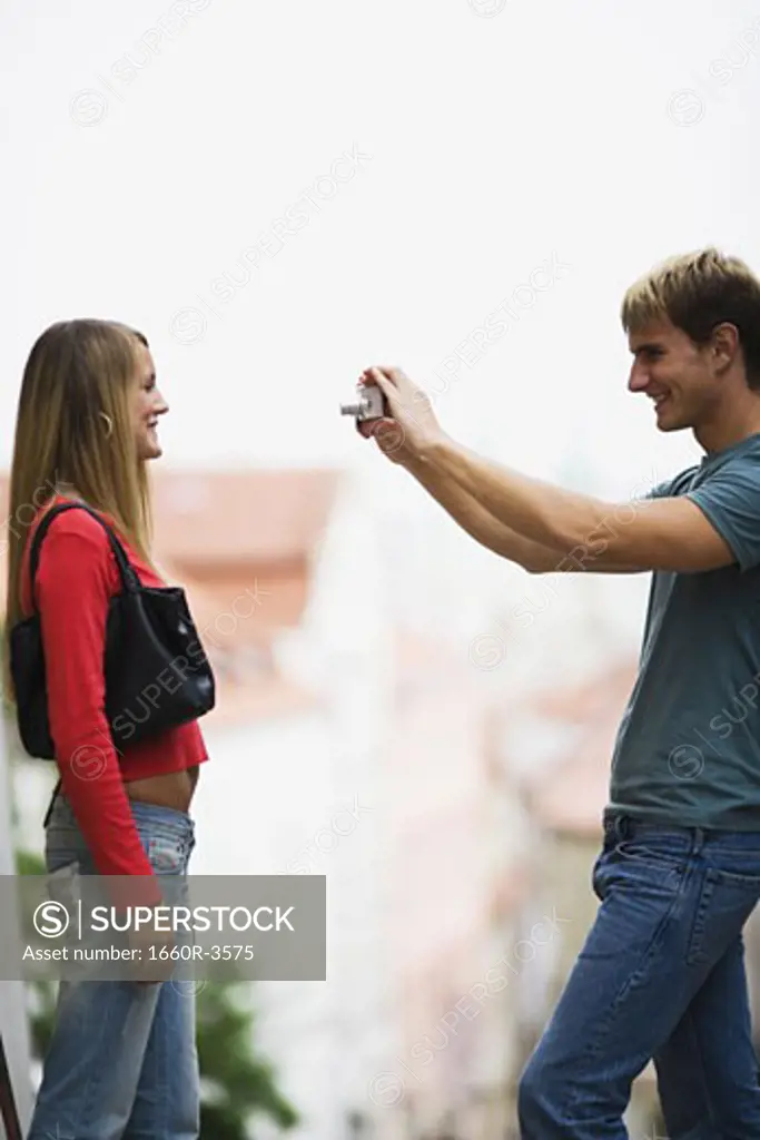 Portrait of a teenage boy taking a photograph of a teenage girl