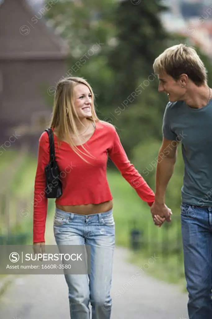 Teenage couple holding hands and walking together on a path