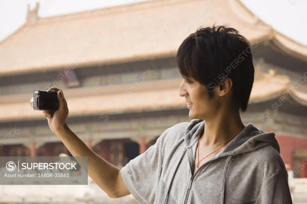 Teenage boy outdoors with digital camera smiling