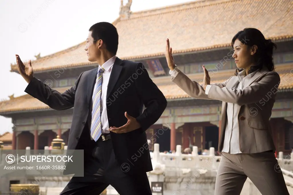 Businesswoman and man doing tai chi outdoors