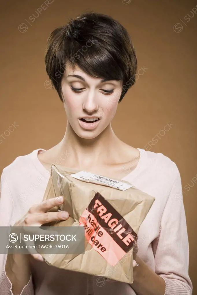 Woman holding crushed cardboard box with fragile label