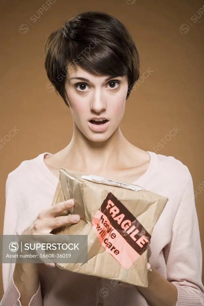 Woman holding crushed cardboard box with fragile label