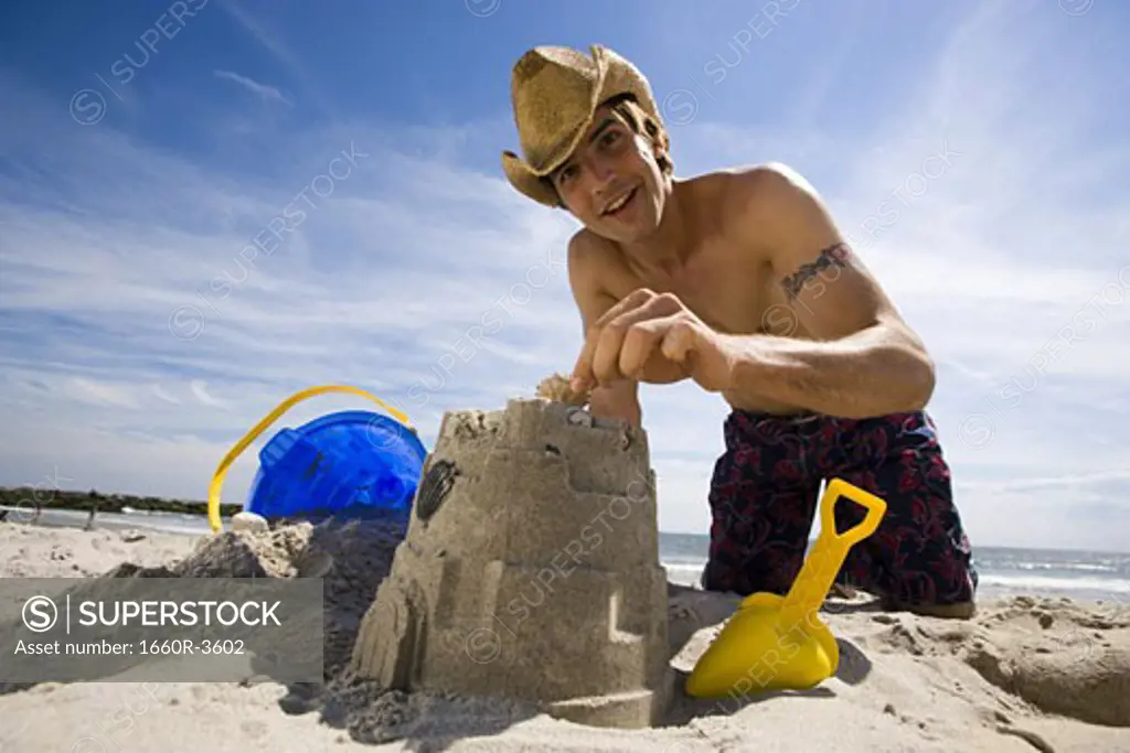Portrait of a young man making a sand castle