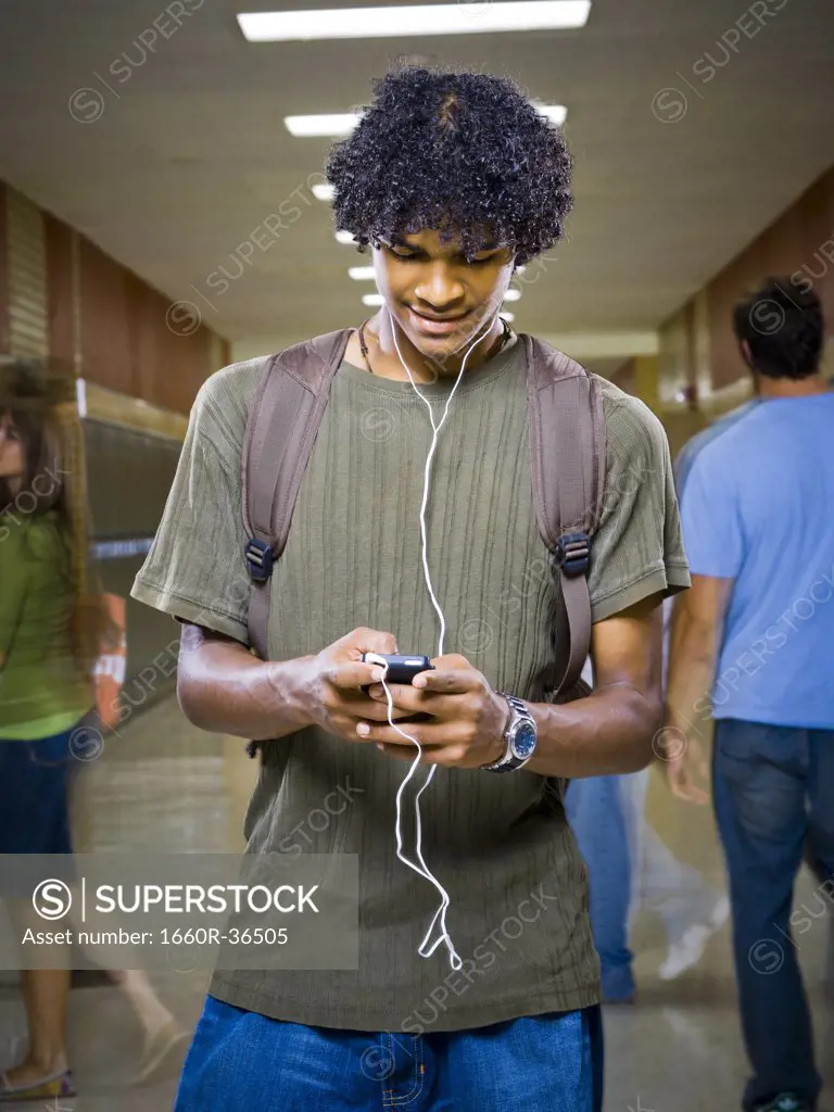 High School boy at school listening to MP3 player.