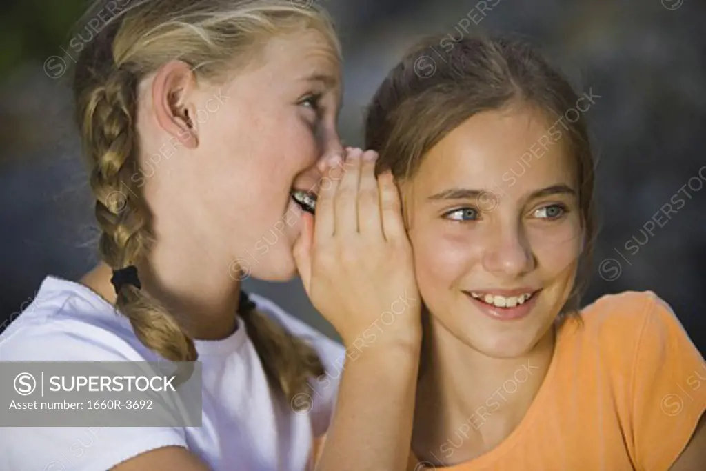 Close-up of a girl whispering into her friend's ear