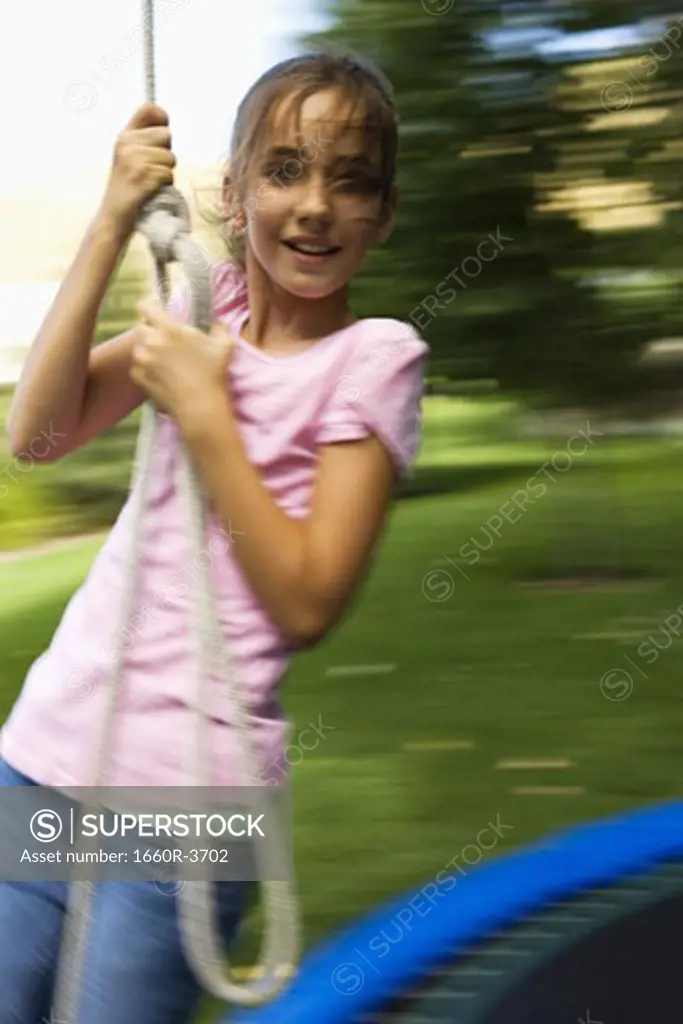Portrait of a girl swinging from a rope