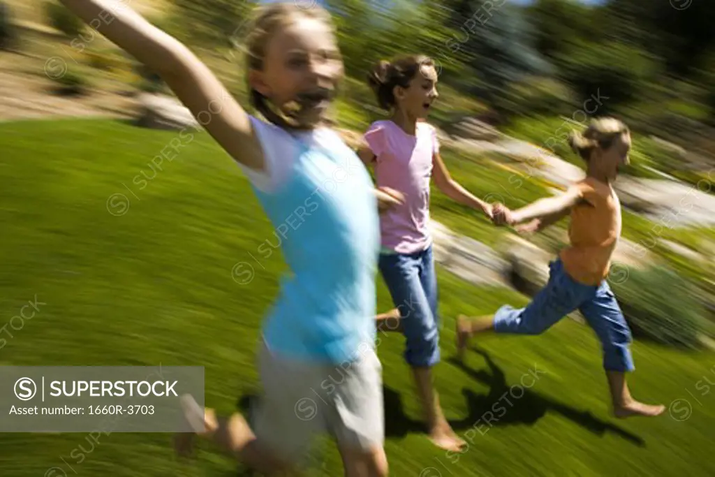 Three girls holding hands and running
