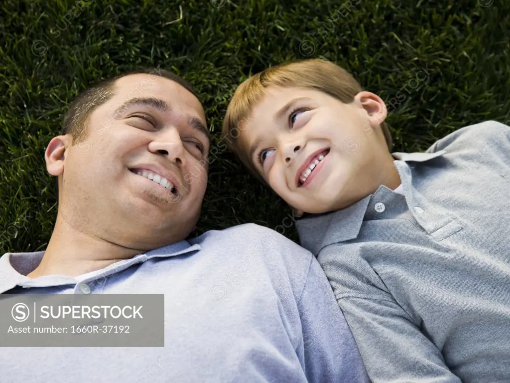 dad and son lying on the grass.
