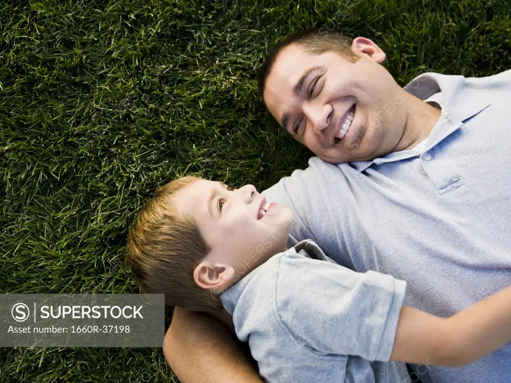 dad and son lying on the grass.