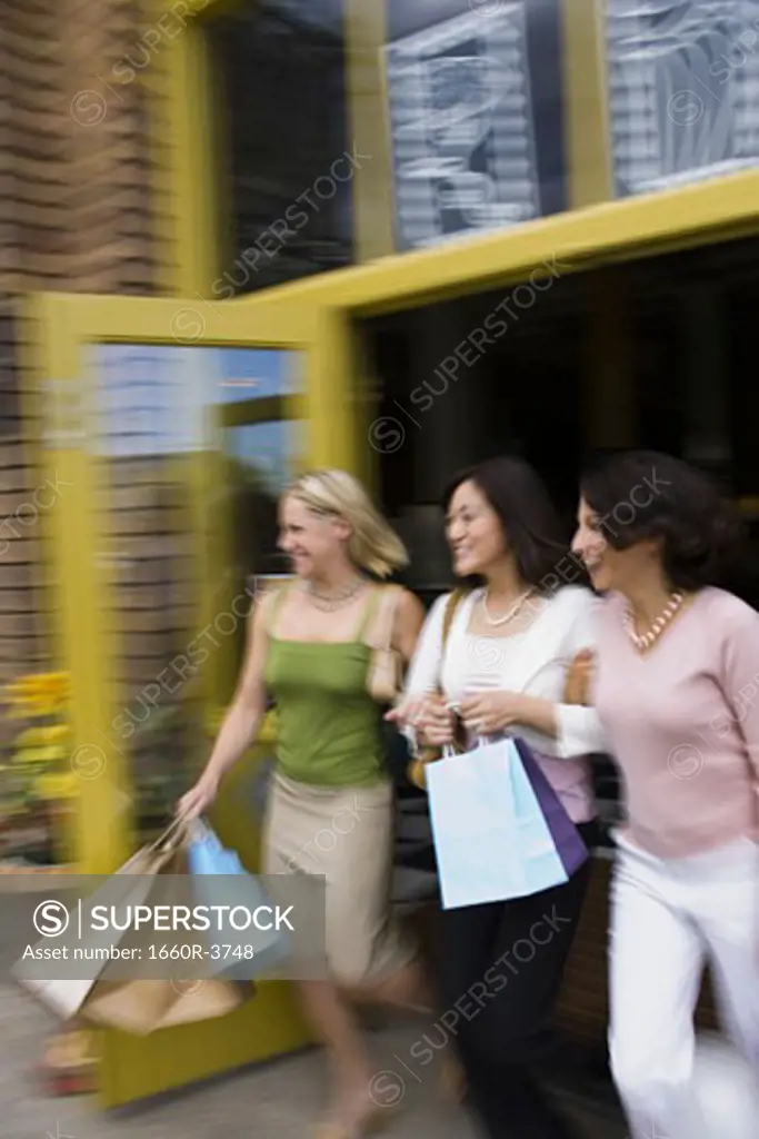 Two young women with an adult woman stepping out of a store