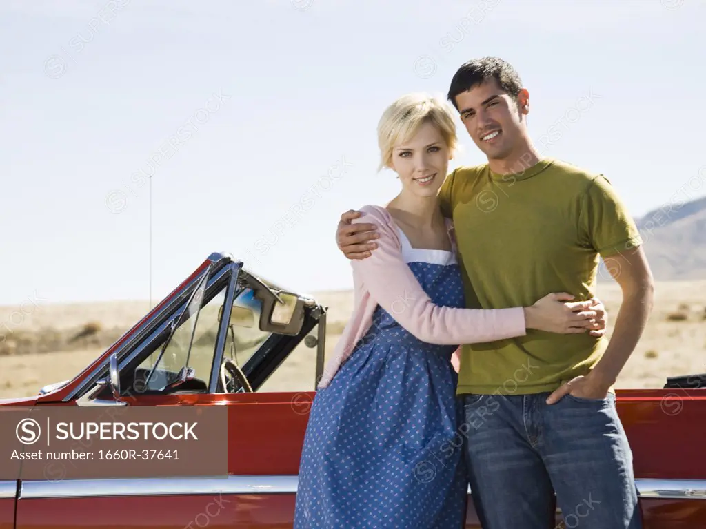 man and woman next to a red convertible