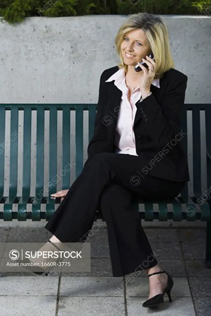 Businesswoman sitting on a bench and talking on a mobile phone