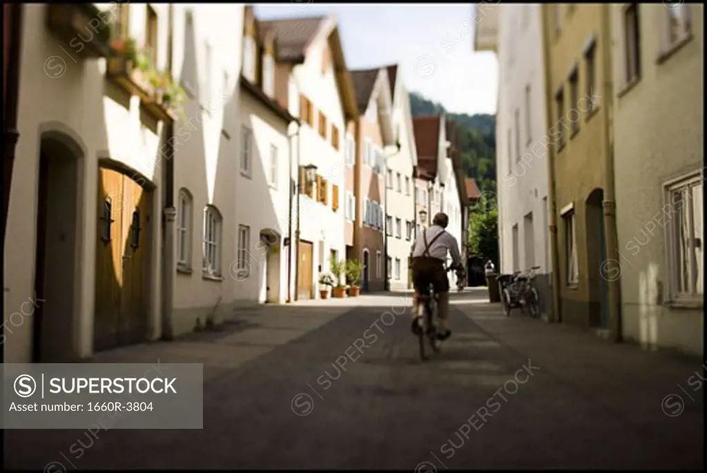 Rear view of a man riding a bicycle in an alley