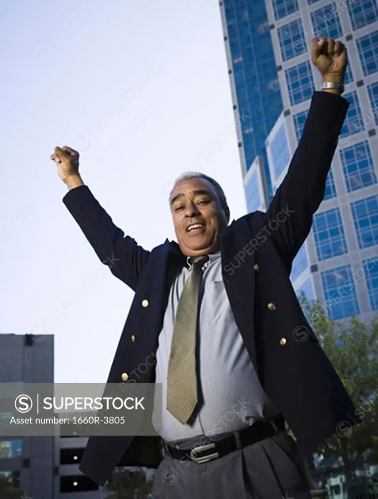 Low angle view of a businessman standing with his arms raised