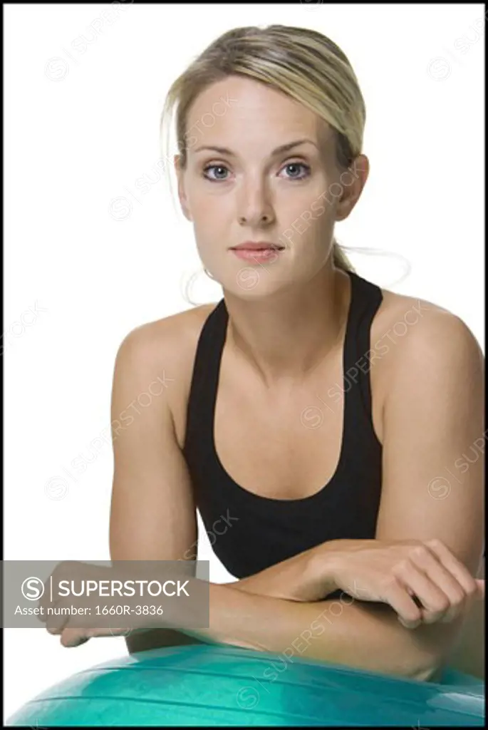 Portrait of a young woman leaning on a fitness ball