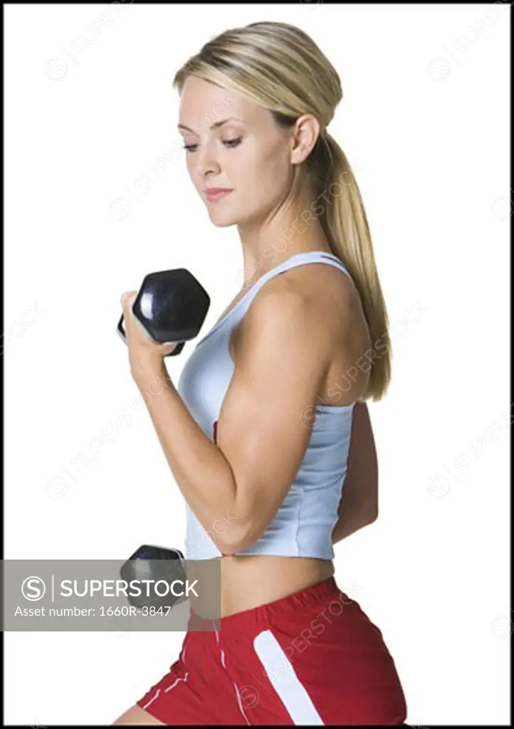 Profile of a young woman exercising with dumbbells