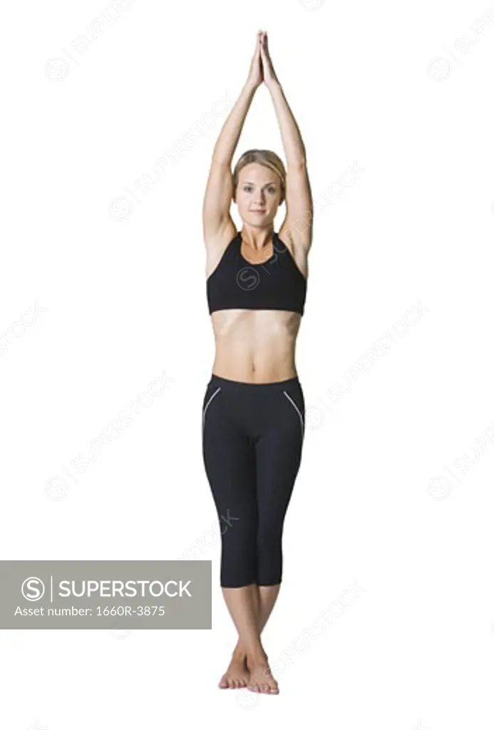 Portrait of a young woman standing with her arms raised and legs crossed