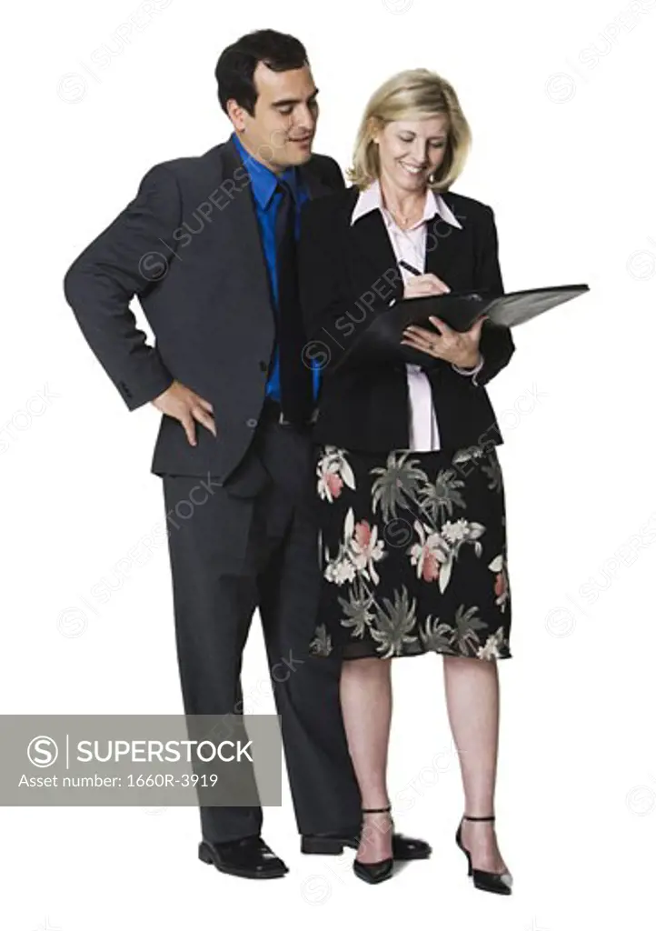 Businesswoman writing in a folder next to a businessman