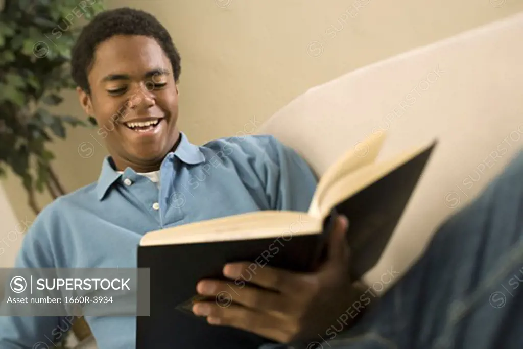 Teenage boy reading a book and smiling