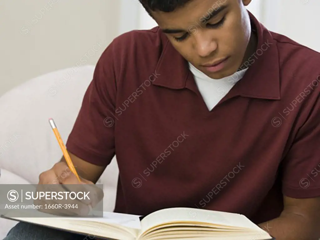 Close-up of a young man writing on a notebook