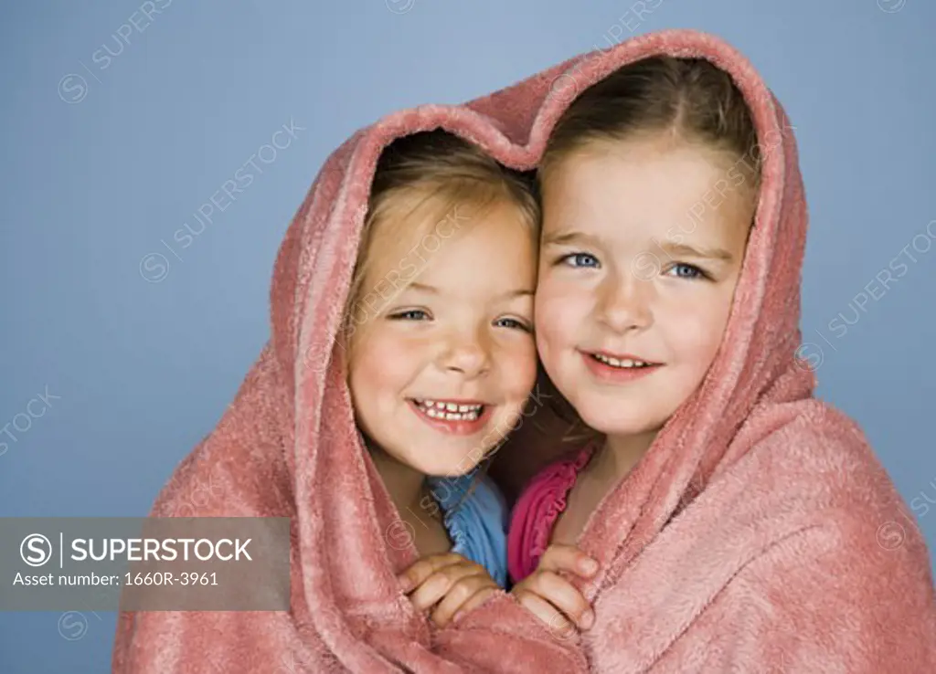 Portrait of two girls under a blanket and smiling