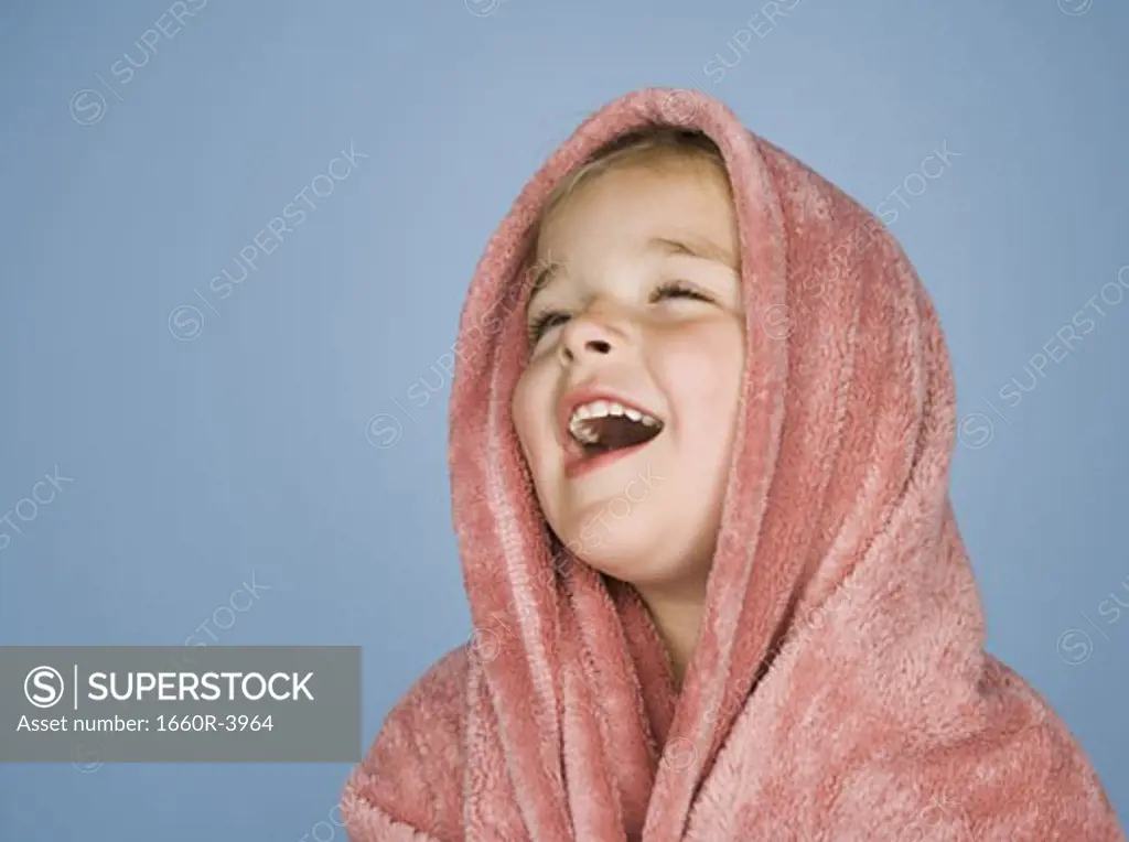Close-up of a girl laughing with a blanket wrapped around her head