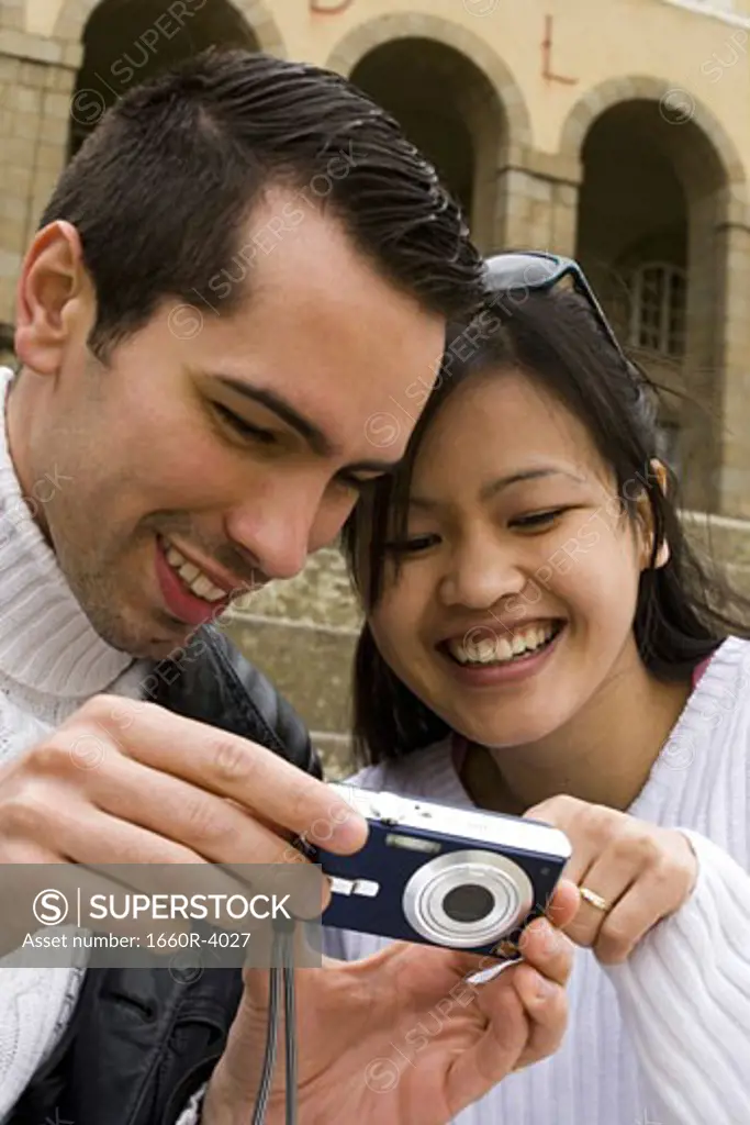 Young man showing a digital camera to a young woman