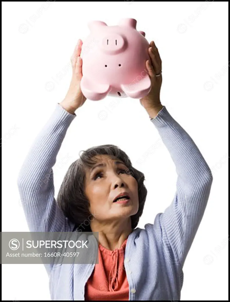 senior woman shaking piggy bank
