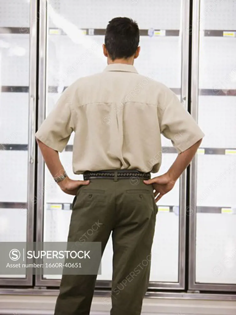 man looking into empty refrigerators at market